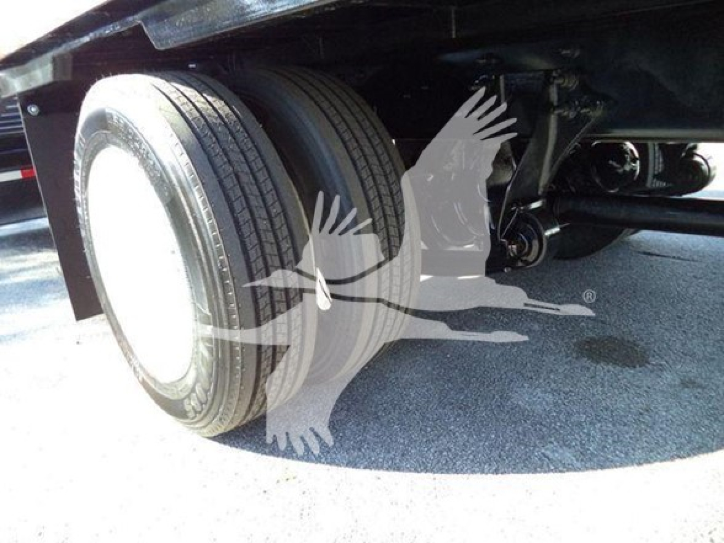 Left rear dual wheels and undercarriage of a 2019 International 4300 auto carrier showing dual rear tires and suspension components.