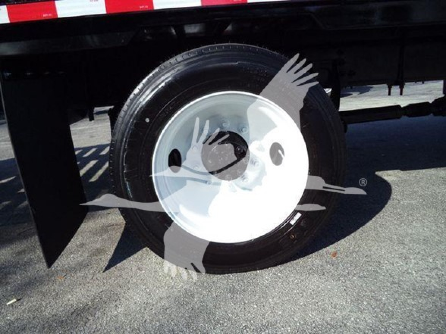 Truck wheel and tire on a 2019 International 4300 stake bed chassis showing a white steel wheel and tire with wheel cover.