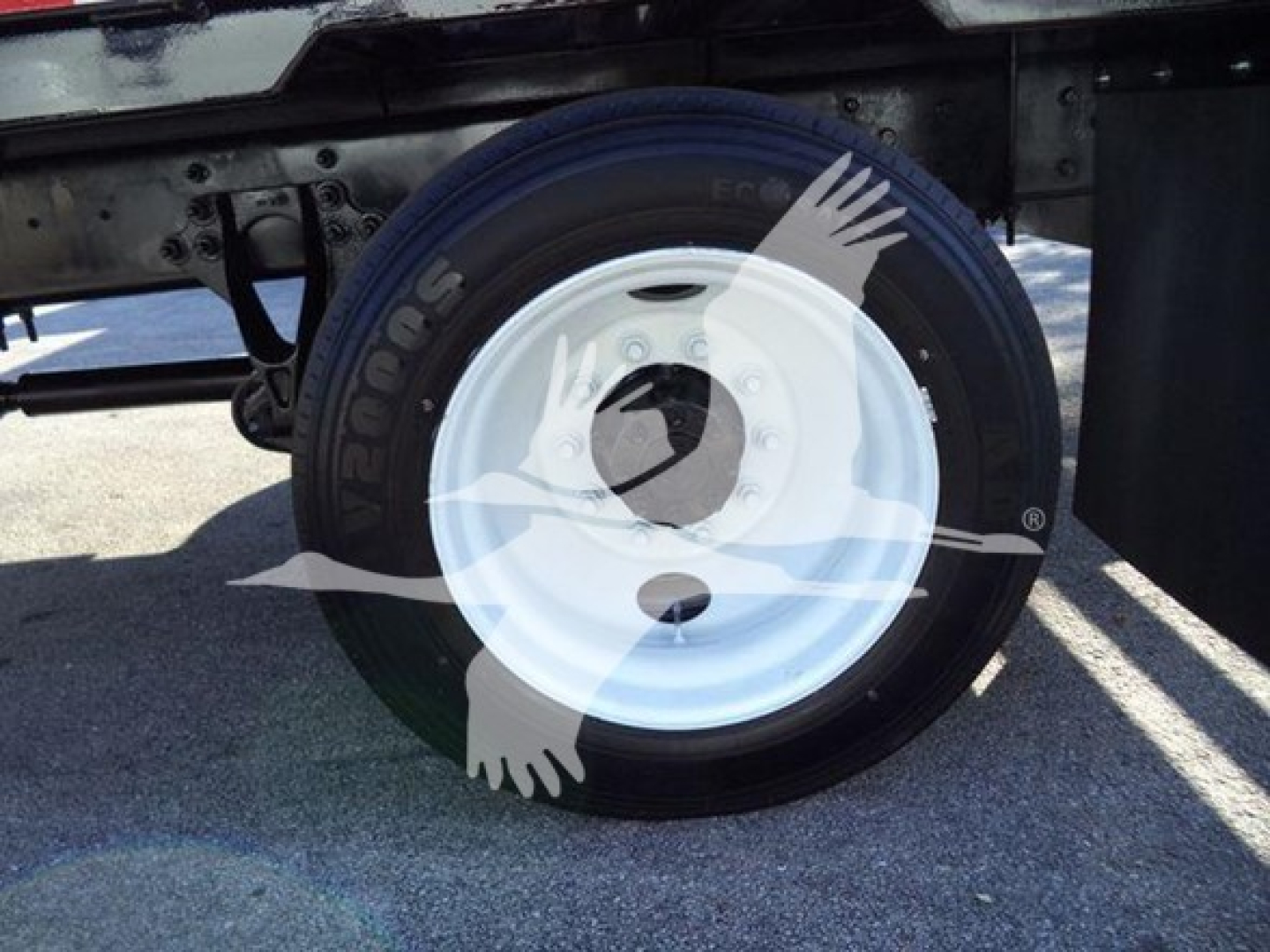 Trailer wheel and tire assembly on a 2019 International 4300 low-profile truck chassis showing a white steel wheel and black tire.