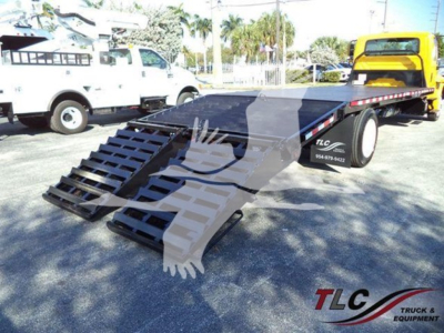 Flatbed tow truck trailer with foldable ramps in an outdoor lot, International 4300 listing, stock number T83445, TLC logo on trailer rail.