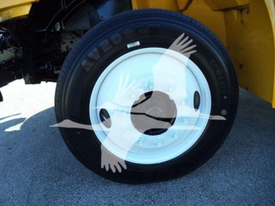 Wheel and tire on front of 2019 International 4300 auto carrier showing tire and white steel wheel with hub cap.