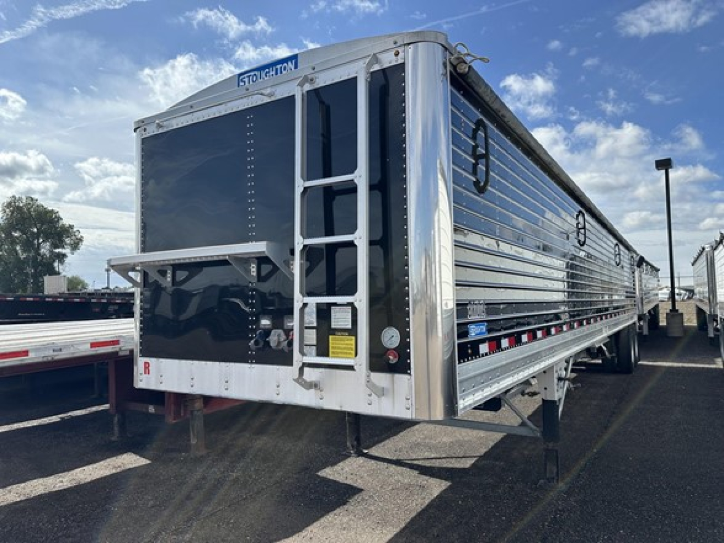 Stoughton air ride grain trailer showing rear doors and access ladder with shiny aluminum panels.