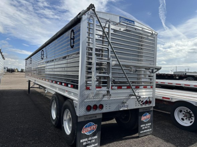 Rear and side view of a Stoughton air ride grain trailer with silver aluminum panels, dual rear axles, ladders, and caution lights. Visible text includes 'Stoughton' on rear upper plate, license plate, and various reflective strips.