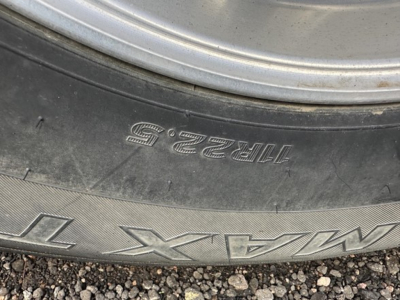 Trailer wheel rim and tire sidewall showing stamped numbers and letters 11232? and MAX-T  on the tire.