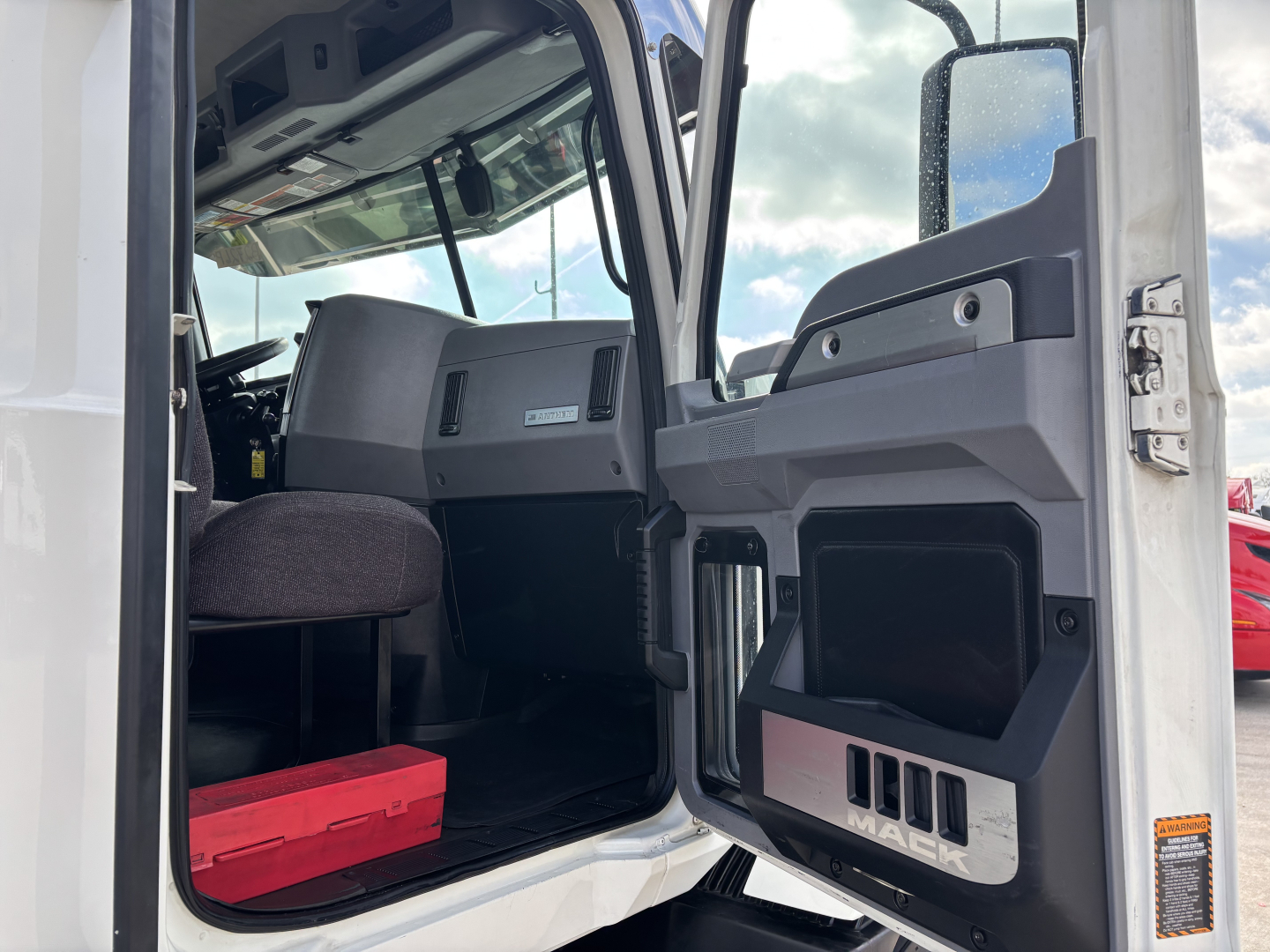 Cab interior of a 2020 Mack AN64T truck showing open door, driver seat, dashboard, and floor mat.