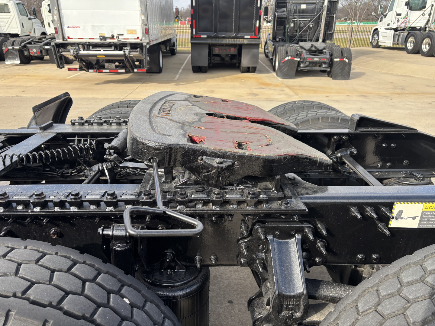 Mack AN64T truck chassis with fifth wheel mount and drivetrain components visible, mid frame view showing tires and mechanical fittings.