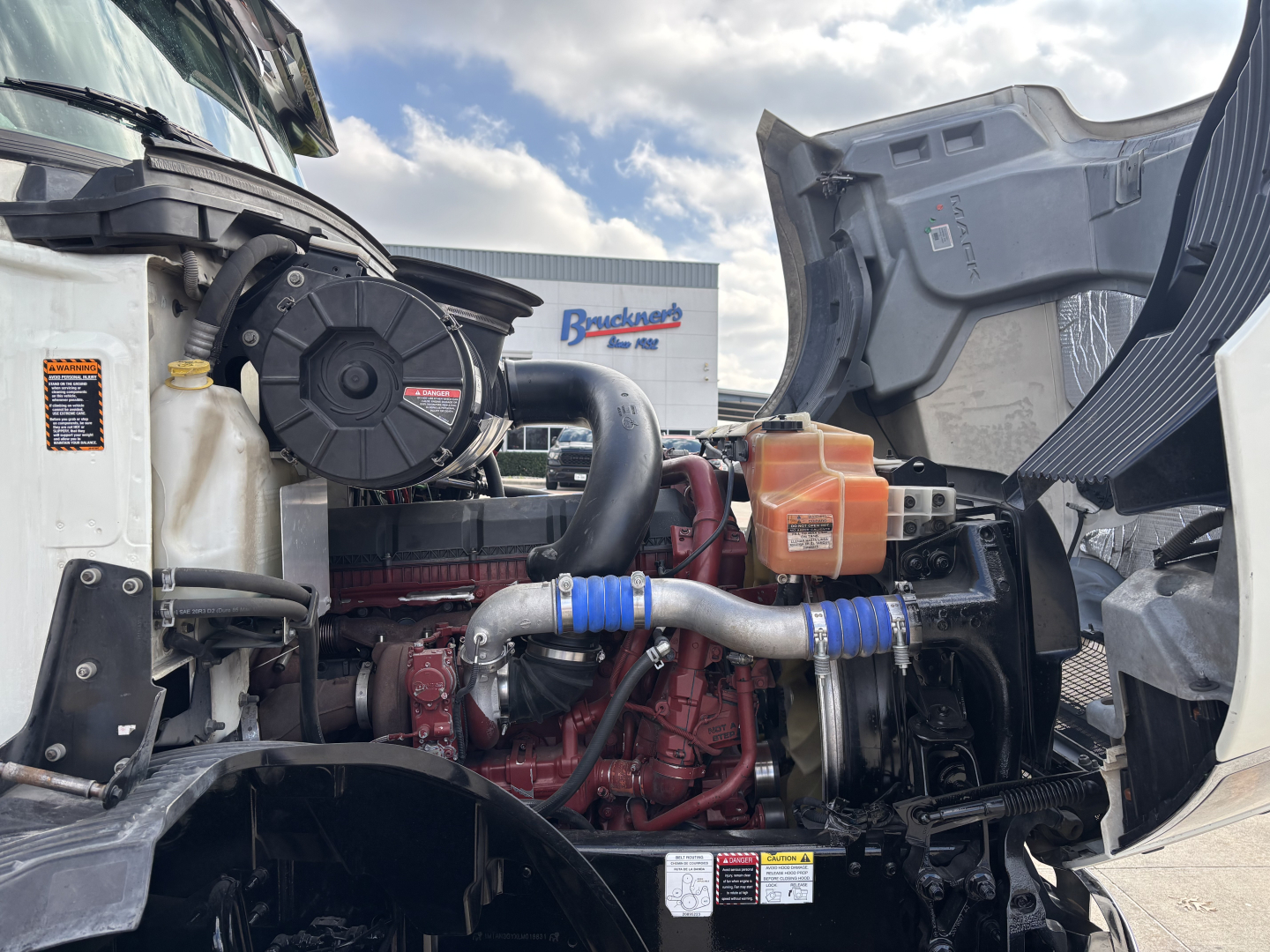 Mack AN64T engine bay showing diesel engine components with hoses, intercooler, and air intake piping.