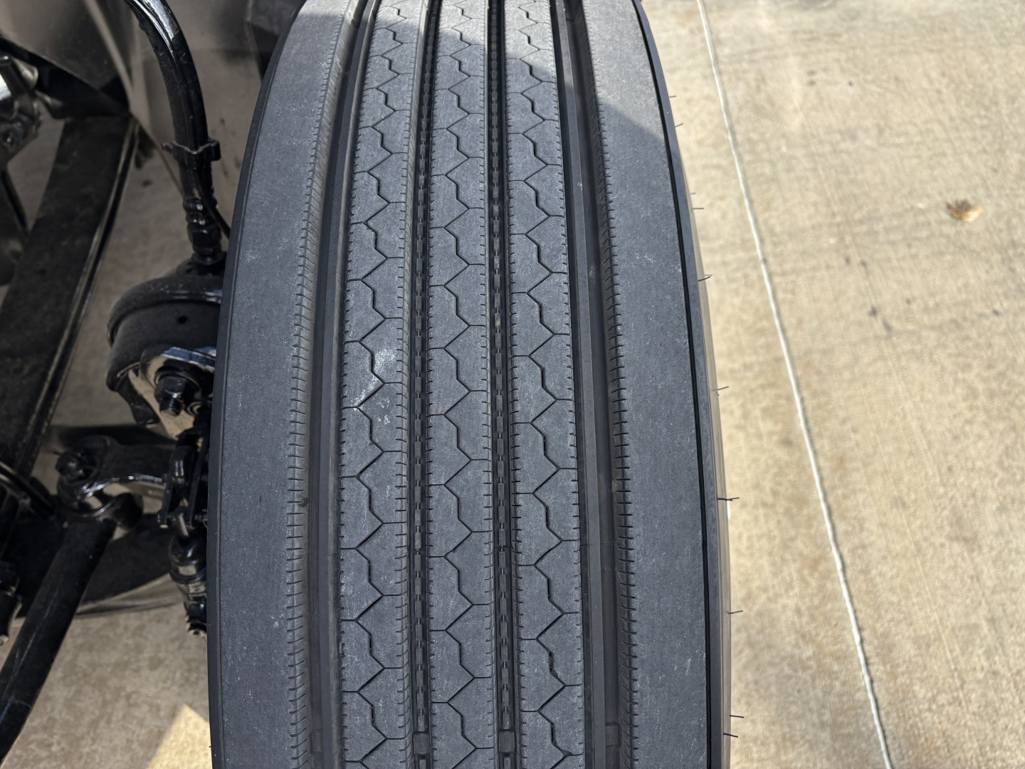 Mack AN64T truck wheel/tire close-up showing tread pattern and suspension components.