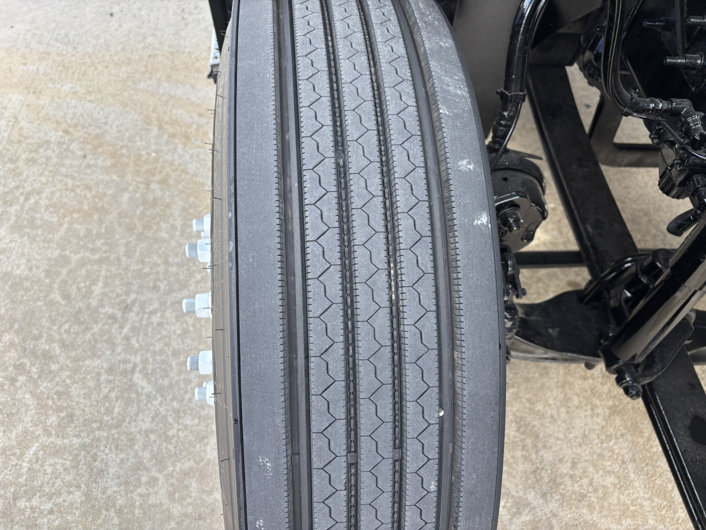 Truck wheel and tire close-up on Mack AN64T conventional daycab showing tread and lug nuts.