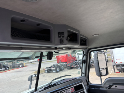 Cab interior of a 2020 Mack AN64T showing overhead storage compartments and dash area with windshield and side mirror.