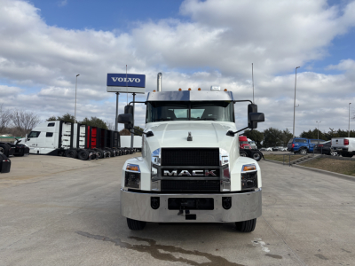 Mack AN64T conventional daycab truck facing camera in dealership lot with Volvo sign in background.
