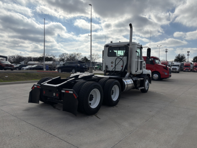 Mack AN64T conventional daycab tractor from rear-left angle showing chassis and dual rear axles, exhaust stack, and fuel tanks. Visible text on the cab and components is not legible.