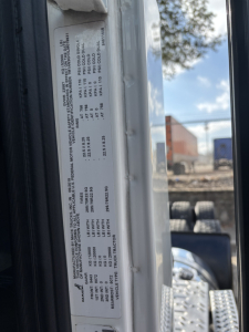 Truck door jamb label showing specifications and weights for a Mack AN64T conventional daycab, including VIN 1M1AN3GYXLM018831 and various tonnage/axle data.