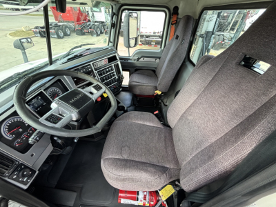 Mack AN64T truck interior showing steering wheel dashboard and two front seats with gray fabric upholstery.