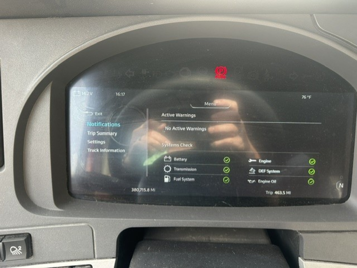 Dashboard screen of a Kenworth T680 showing system warnings and check marks for various subsystems, with a red warning indicator at top and a time/weather reading 76°F.