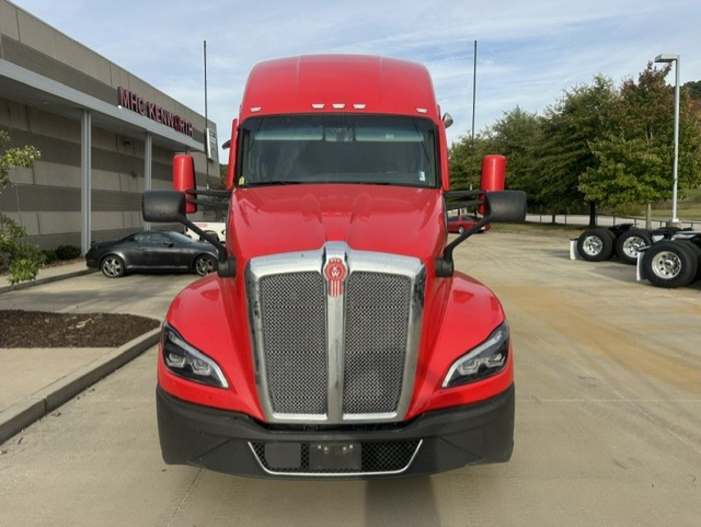 Kenworth T680 front view showing bold chrome grille, red cab, and dual rearview mirrors.