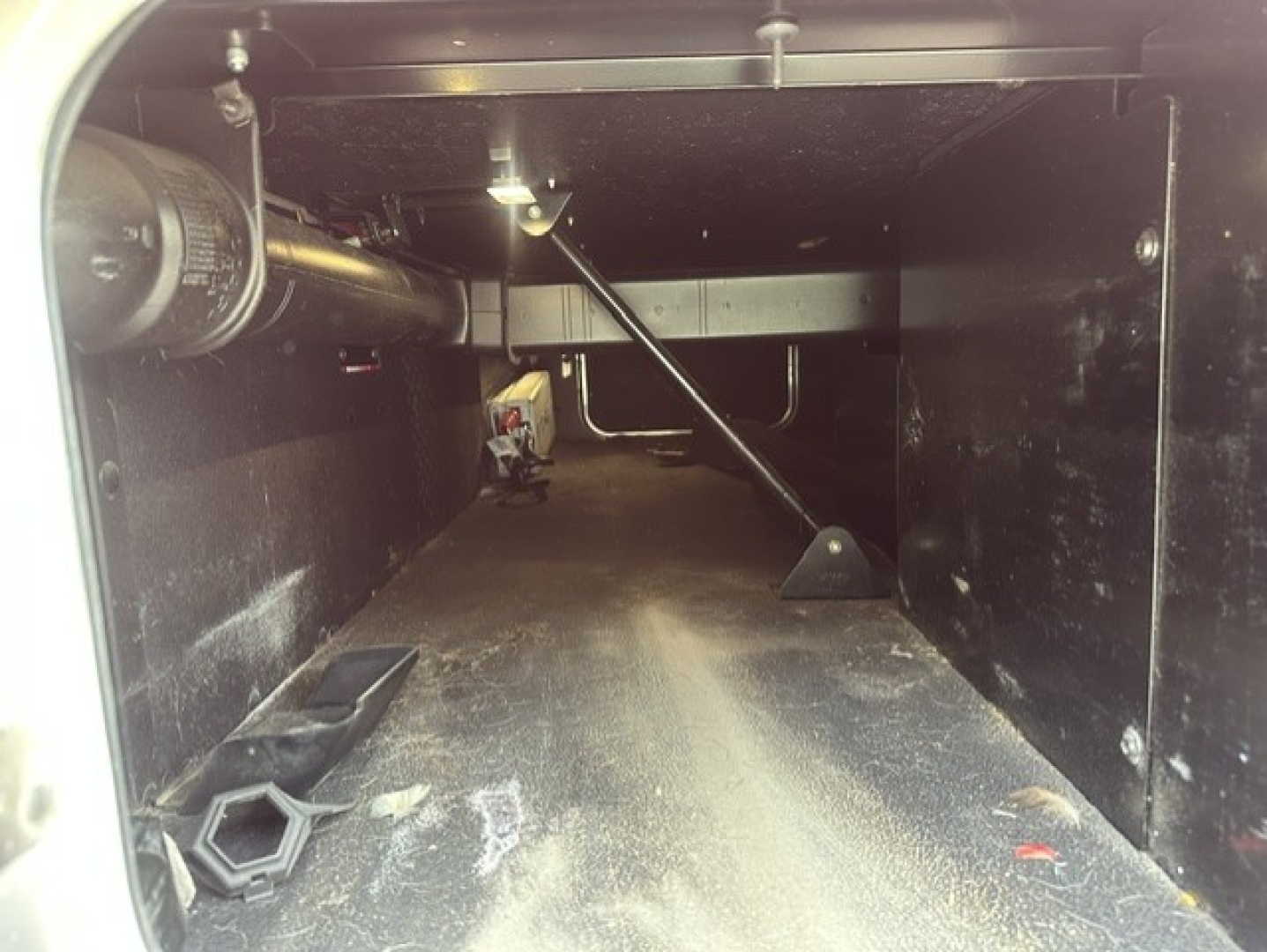 Kenworth T680 cab/storage area with metal shelves and wiring; empty storage bay with dust and small tools visible