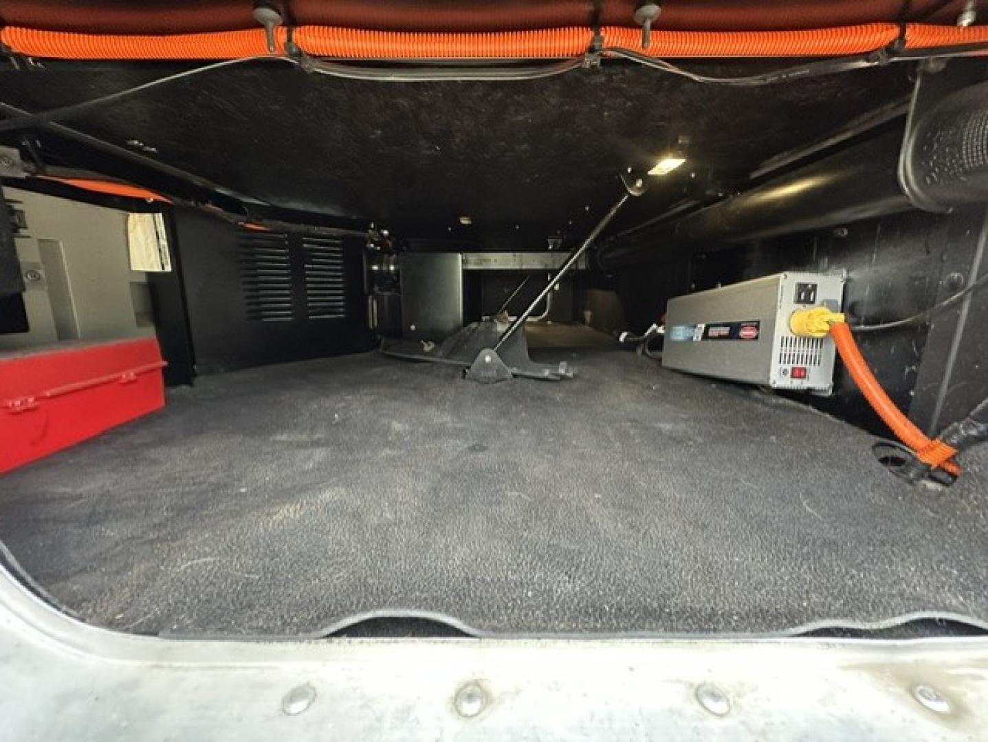 Kenworth T680 cab interior rear cargo area with storage and electrical equipment visible under the floor mats.