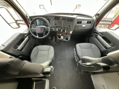 Kenworth T680 cab interior showing steering wheel, dashboard, and two front seats.