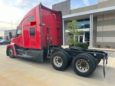 Kenworth T680 tractor in red, side view showing rear axles and fifth wheel with cab interior not visible.