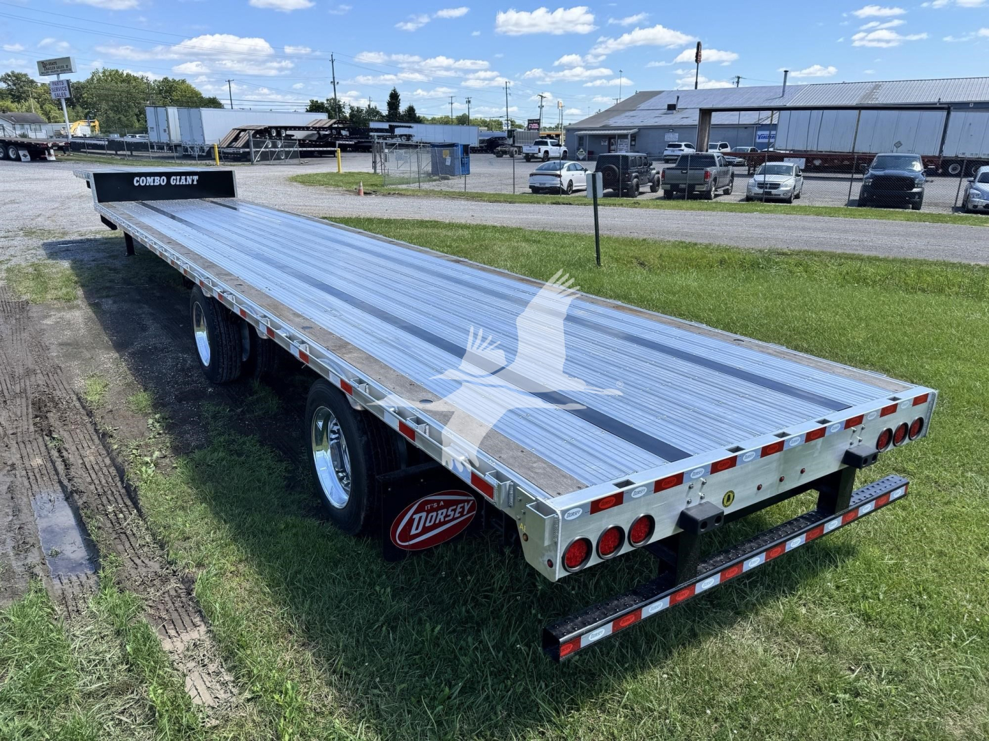 Flatbed trailer showing long aluminum deck with dual rear axles and red-and-white rear lights, Dorsey branding on mudflaps, stock number VED49511 visible.