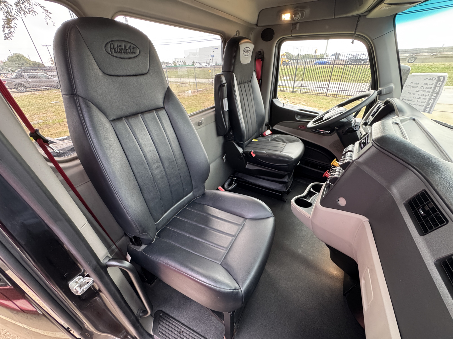Peterbilt 579 cab interior showing driver and passenger seats with dashboard and steering wheel visible.