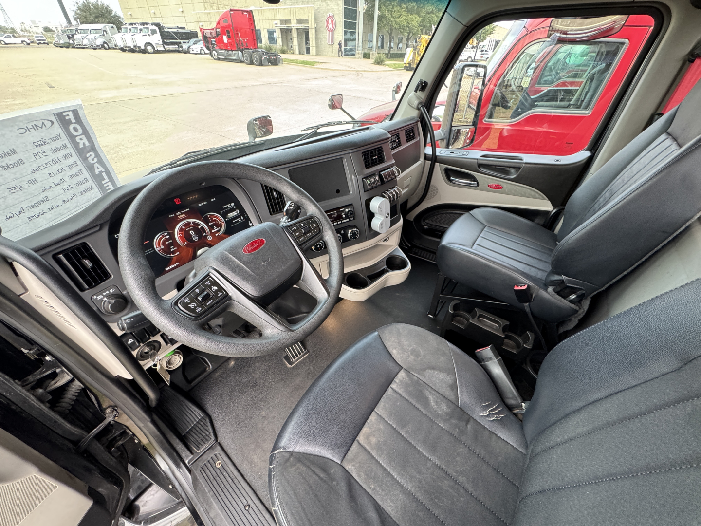 Peterbilt 579 cab interior showing steering wheel, dashboard gauges, center console, and front seats.