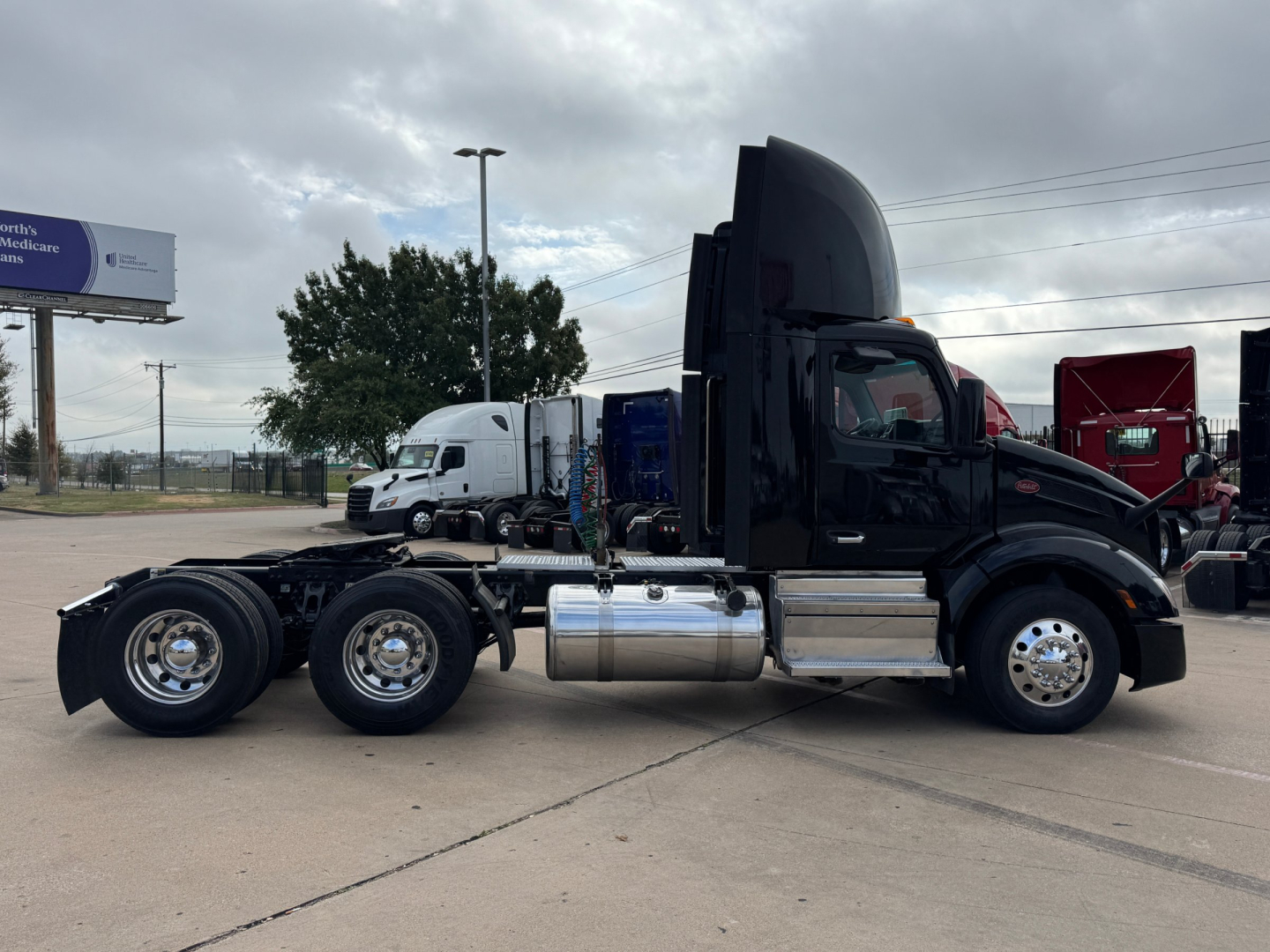 Peterbilt 579 conventional daycab truck side view showing chrome fuel tanks and dual rear axles.