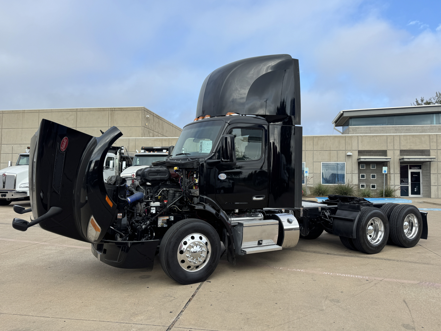 Peterbilt 579 in-service daycab truck with hood open showing engine and components, black cab and chrome fuel tanks, 6x4 dual rear axles.