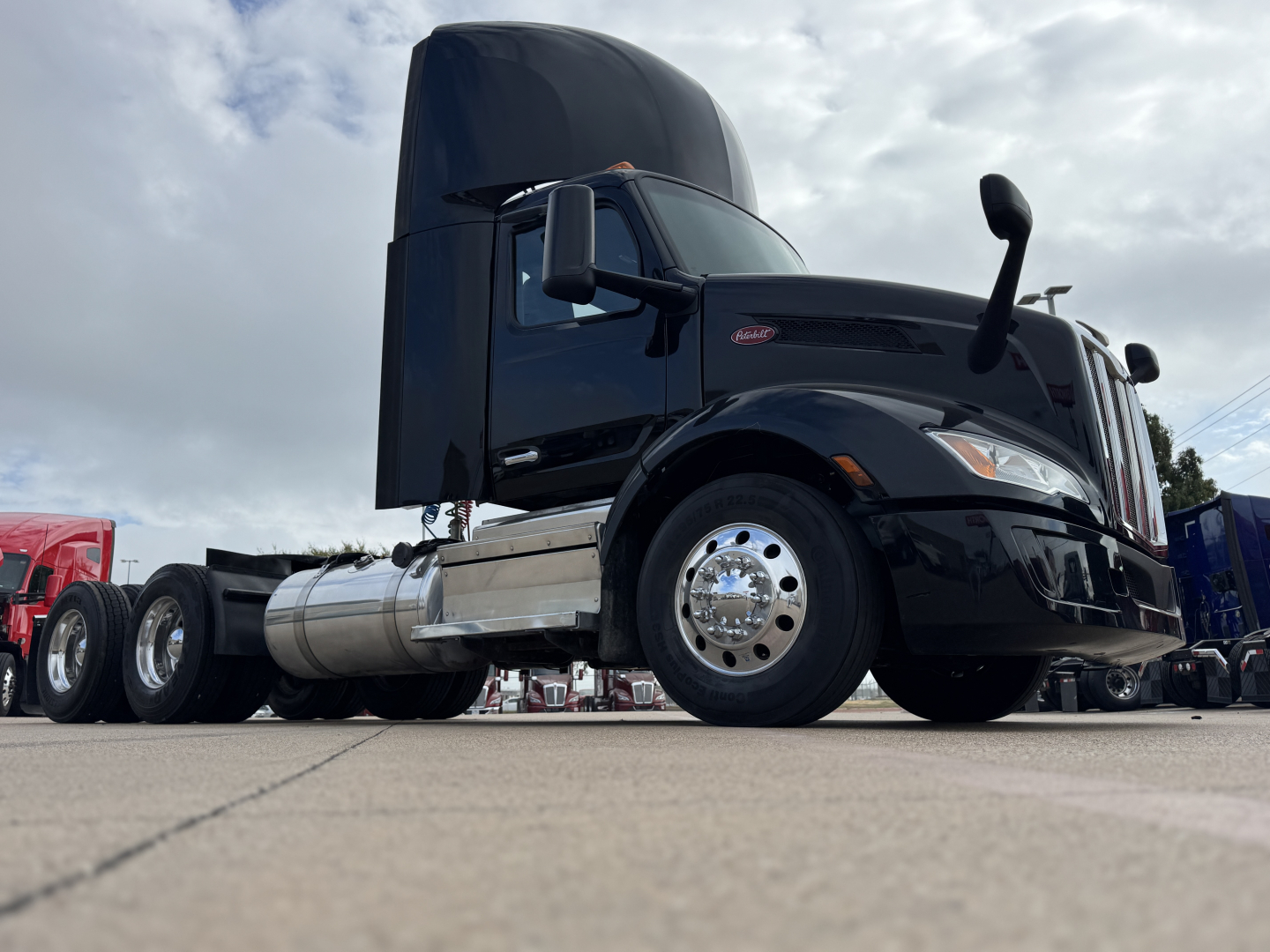 Peterbilt 579 daycab truck in black, side view showing cab area and fuel tanks.