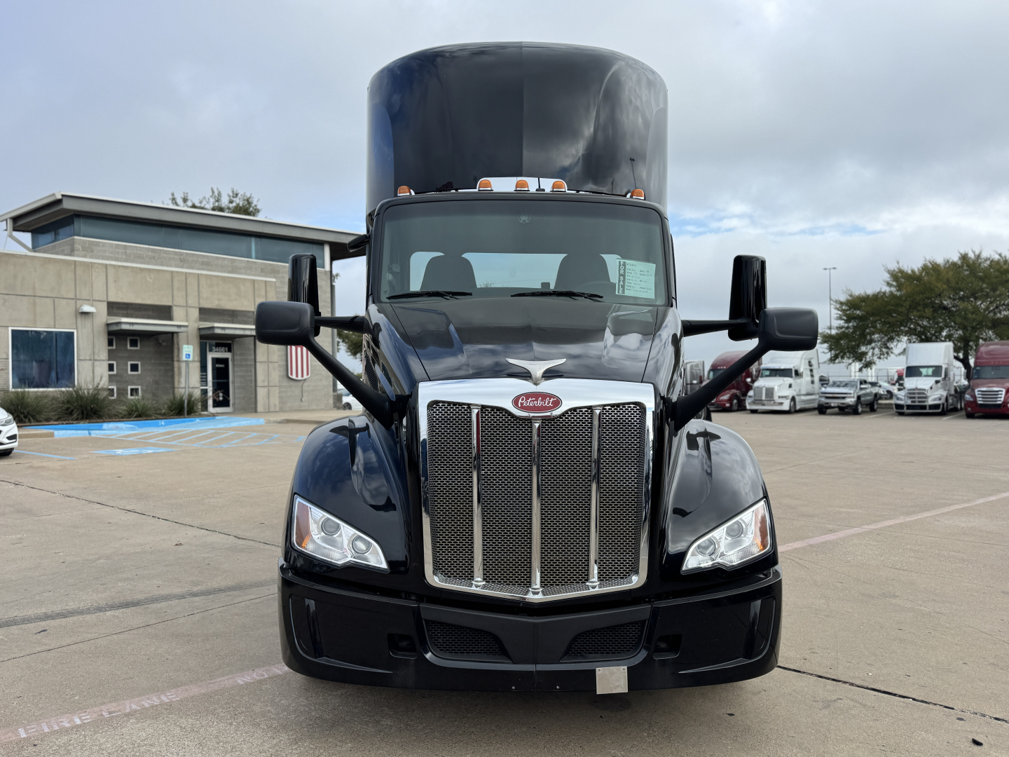 Peterbilt 579 front view with chrome grille and headlights; logo on grille, large hood, cab mirrors visible.
