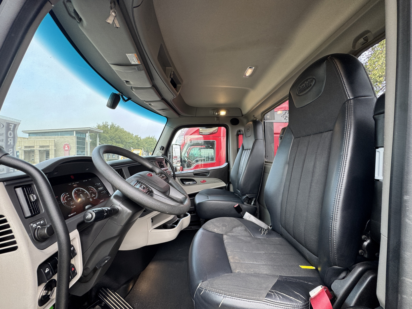 Peterbilt 579 cab interior with driver seat and dashboard; steering wheel, instrument cluster, and doorway visible.