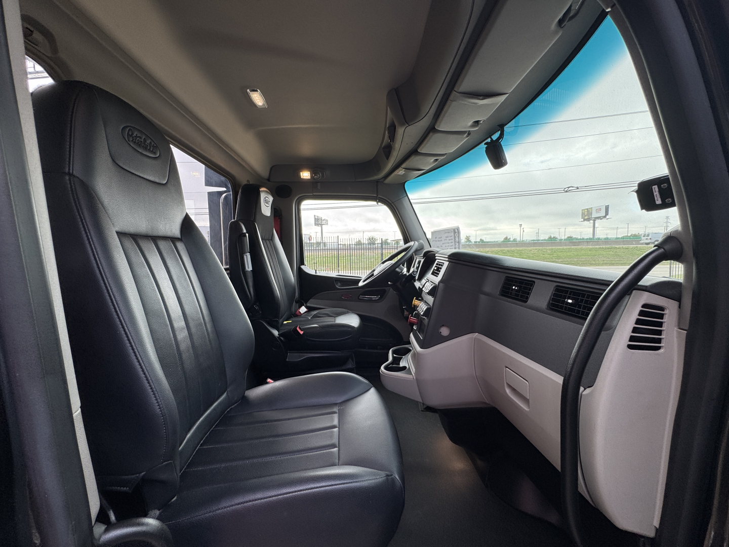 Peterbilt 579 interior cab view showing driver and passenger seats, dashboard, steering wheel, and center console.