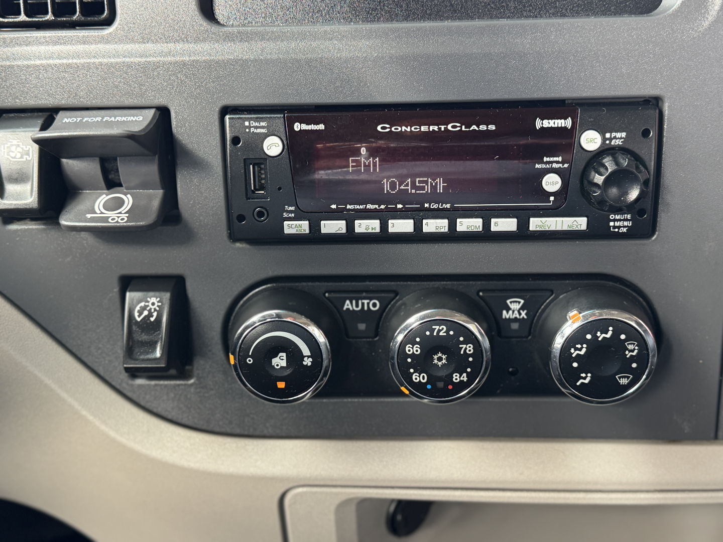 Peterbilt 579 interior dash showing center console with ConcertClass radio displaying FM1 104.5, climate control dials, and various switches.