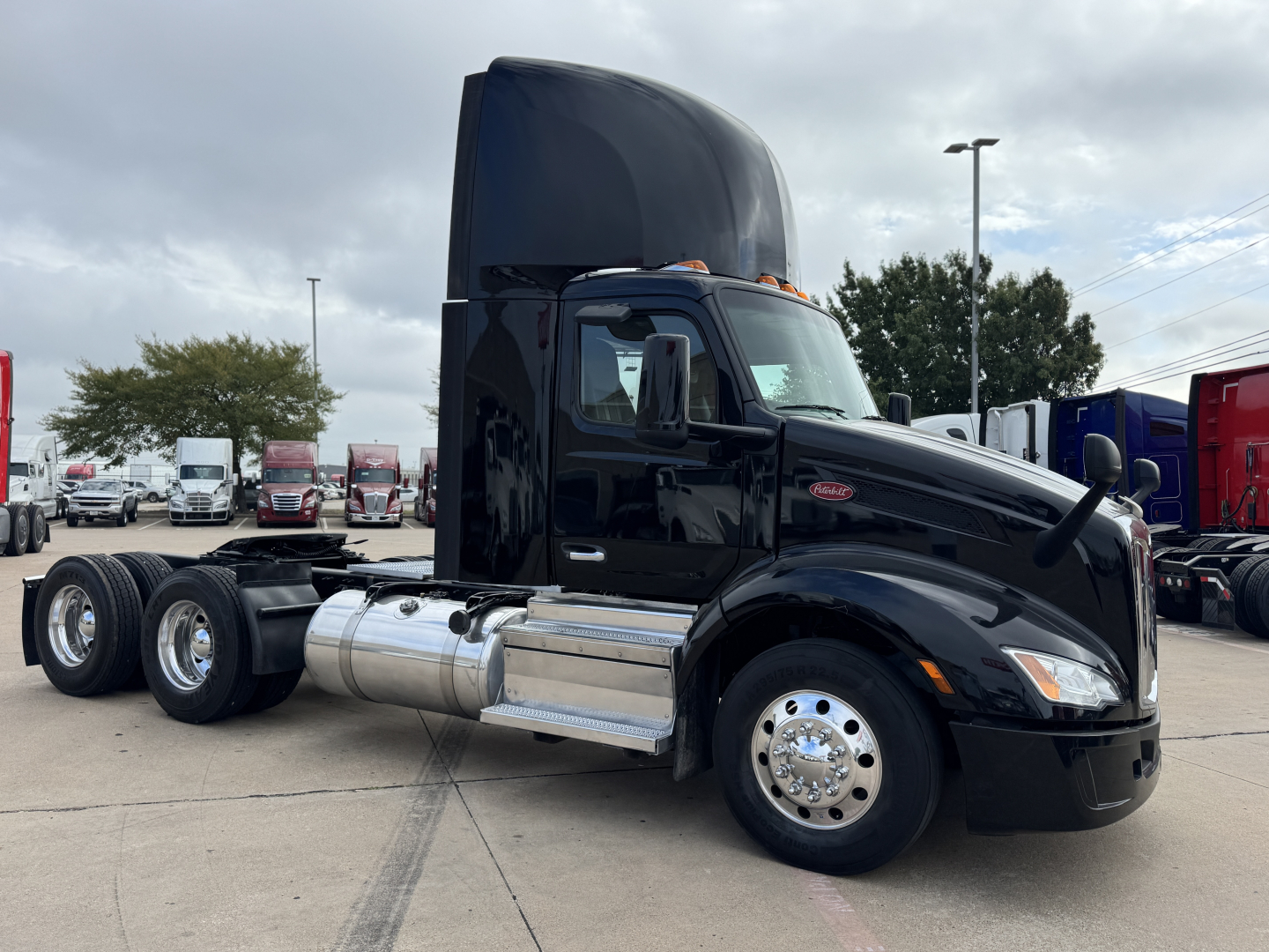 Peterbilt 579 tractor in black with elevated sleeper cab, side view showing fuel tanks and dual rear axles. Visible text includes Peterbilt emblem on front grille and chrome fuel tanks.