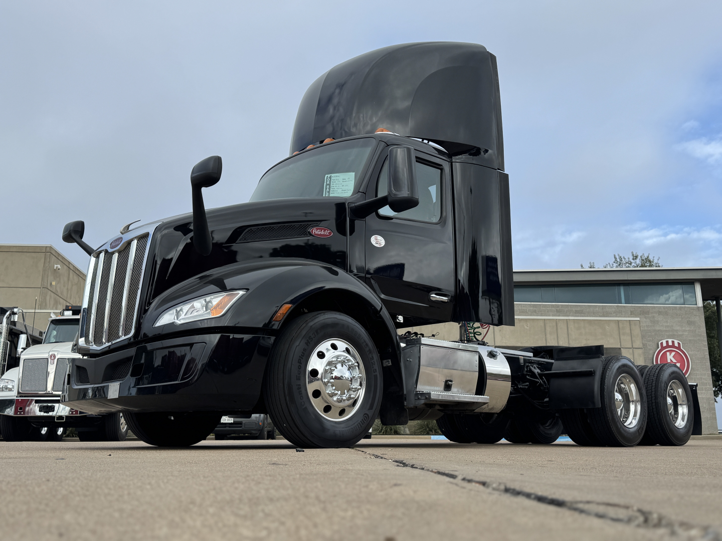 Peterbilt 579 truck cab with raised air deflector and open hood showing front wheel and dual rear axles.
