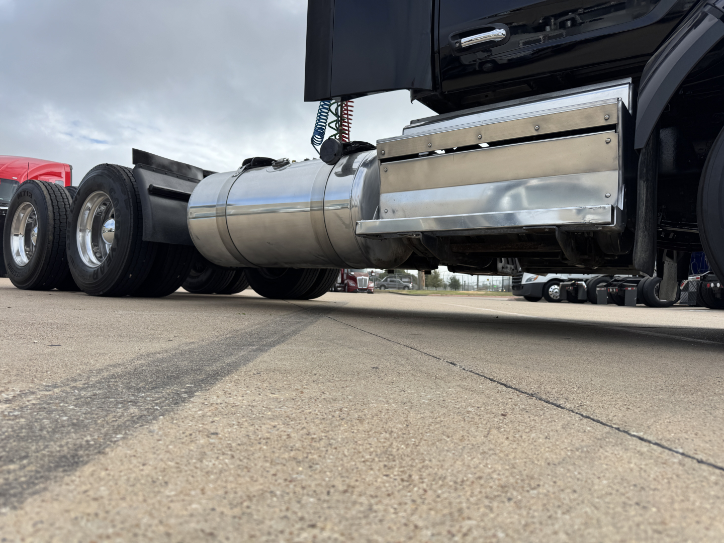Peterbilt 579 truck underside showing polished stainless fuel tank and side step, dual rear axles with chrome wheels visible.