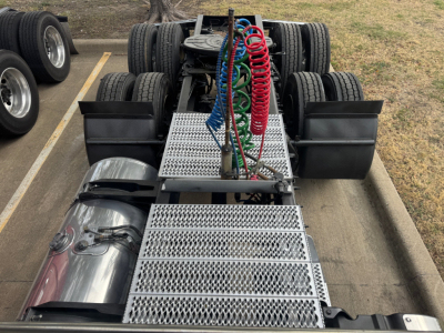 Peterbilt 579 truck chassis showing vertical exhaust and colored air lines with chrome fuel tank and diamond plate steps.