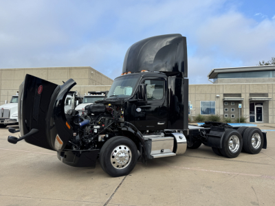 Peterbilt 579 in-service daycab truck with hood open showing engine and components, black cab and chrome fuel tanks, 6x4 dual rear axles.