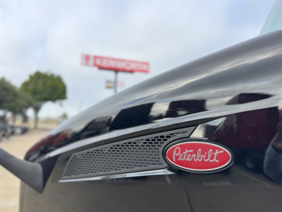Peterbilt emblem on a 2022 Peterbilt 579 front fender with chrome grille vent and badge in focus.