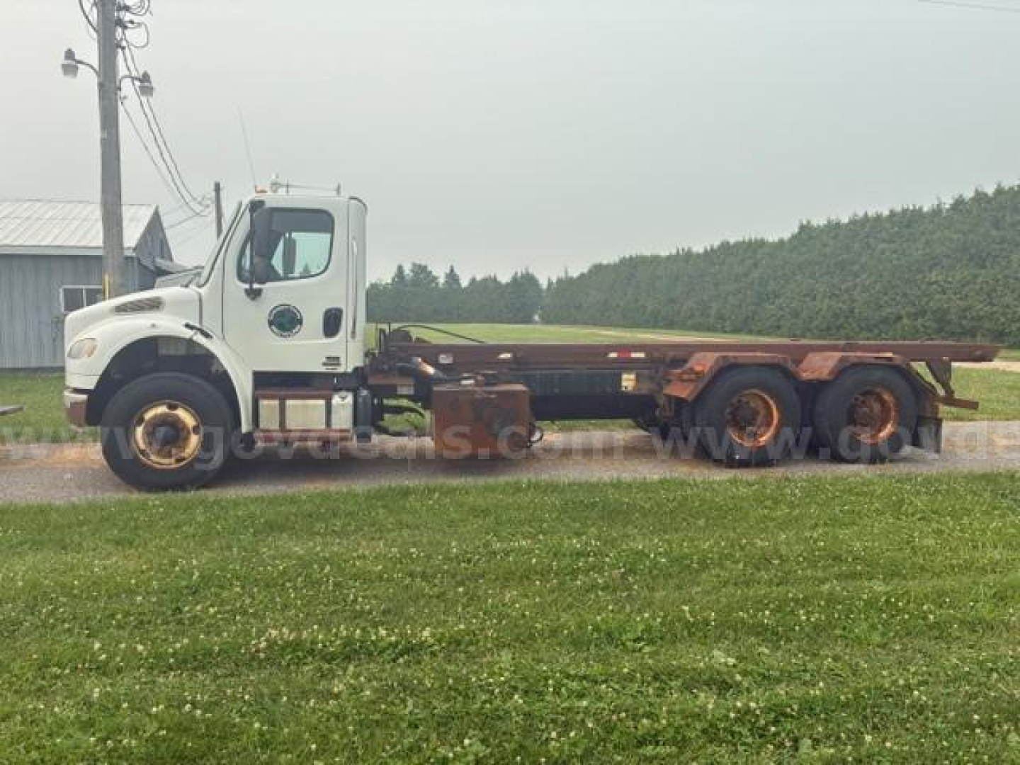 Cab and chassis truck with flatbed showing Freightliner M2-106 style cab; text on door and side panels/tires not legible.