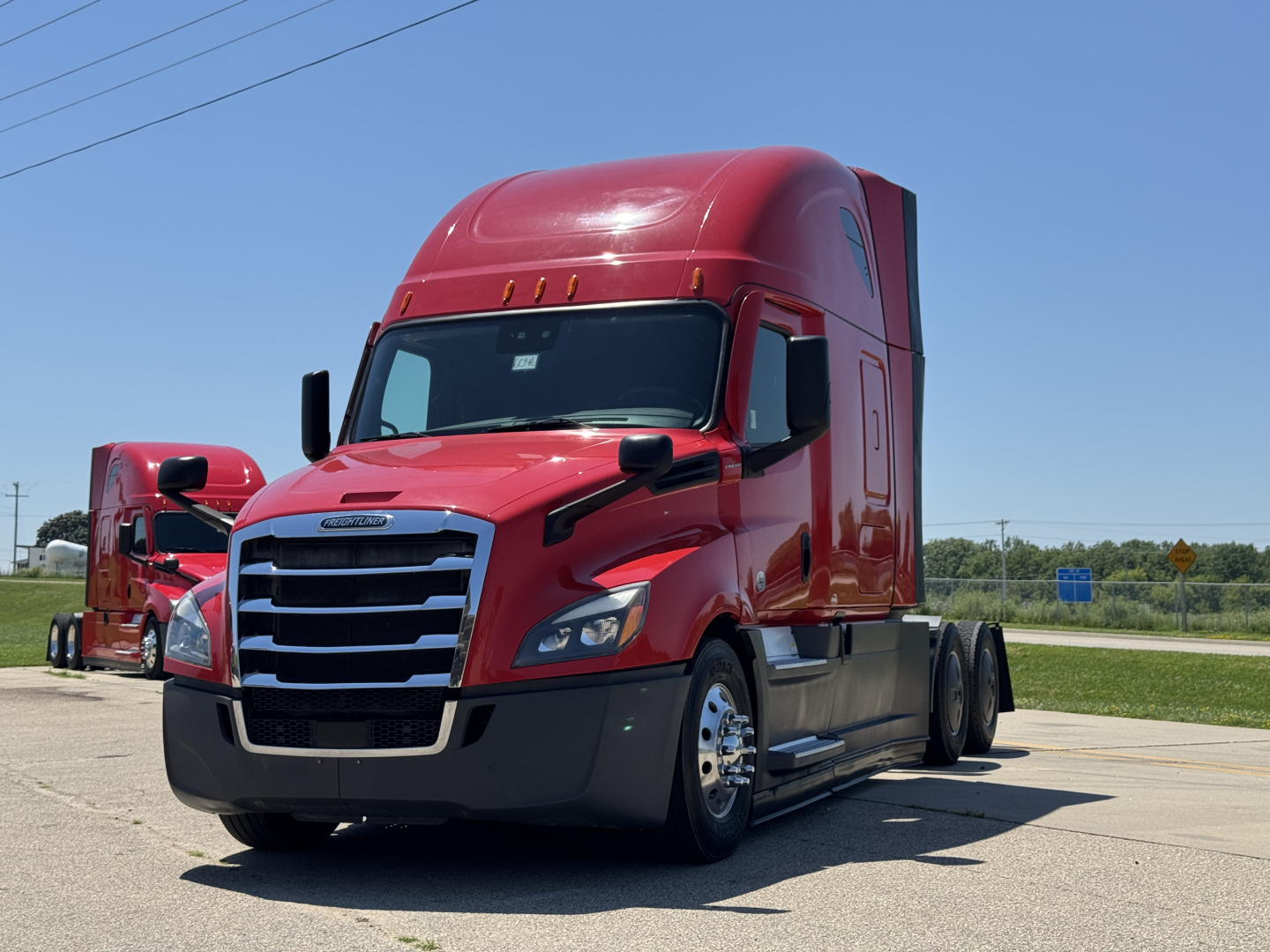 Conventional sleeper truck showing red 2023 Freightliner Cascadia 126 front-quarter view with chrome grille and raised sleeper, side fuel tanks, and dual rear axles.