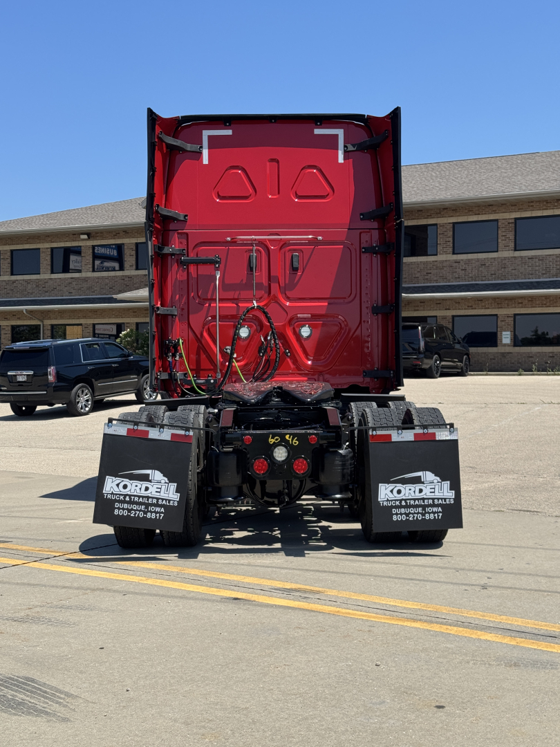 Rear view of a 2023 Freightliner Cascadia 126 with red cab facing away, showing trailer connections and back of tractor, stock number plate visible.