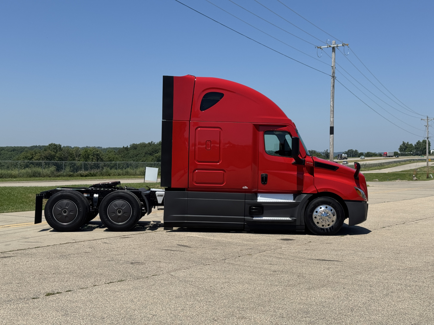 Red 2023 Freightliner Cascadia 126 sleeper tractor, side view, long cab with black chassis, no trailer attached.