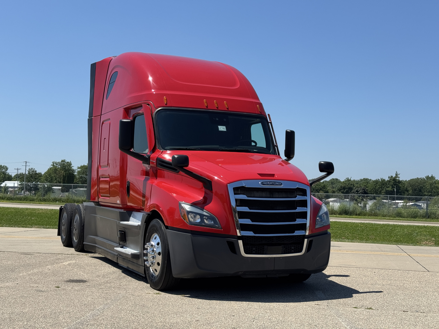 Freightliner Cascadia 126 truck in red, front three-quarter view showing Cab and aerodynamic design, chrome grille, headlights, and side mirrors.