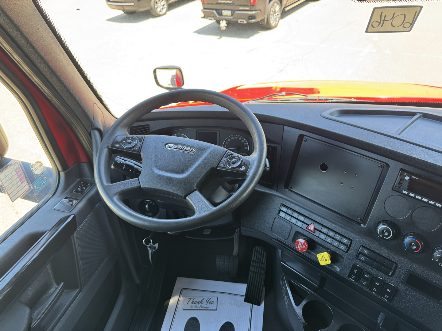Freightliner Cascadia truck cabin interior showing steering wheel, dashboard with large touchscreen display, and control panel.