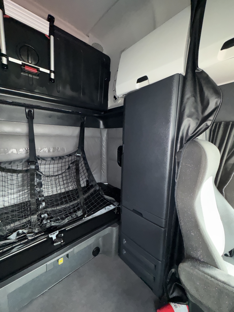 Freightliner Cascadia interior sleeper cab showing storage net and partition with seating area.