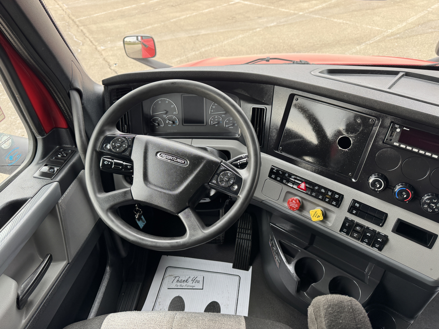 Cab interior of a 2023 Freightliner Cascadia 126 conventional sleeper showing steering wheel, dashboard with gauges, center console, and unidentified controls.