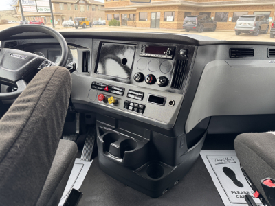 Truck dash and steering wheel interior showing Cab controls, cup holders, and dashboard panels in a Freightliner Cascadia 126 cab.