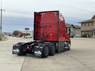 Freightliner Cascadia 126 tractor-trailer rear view showing red sleeper cab and dual rear axle with mud flaps and bumper area.